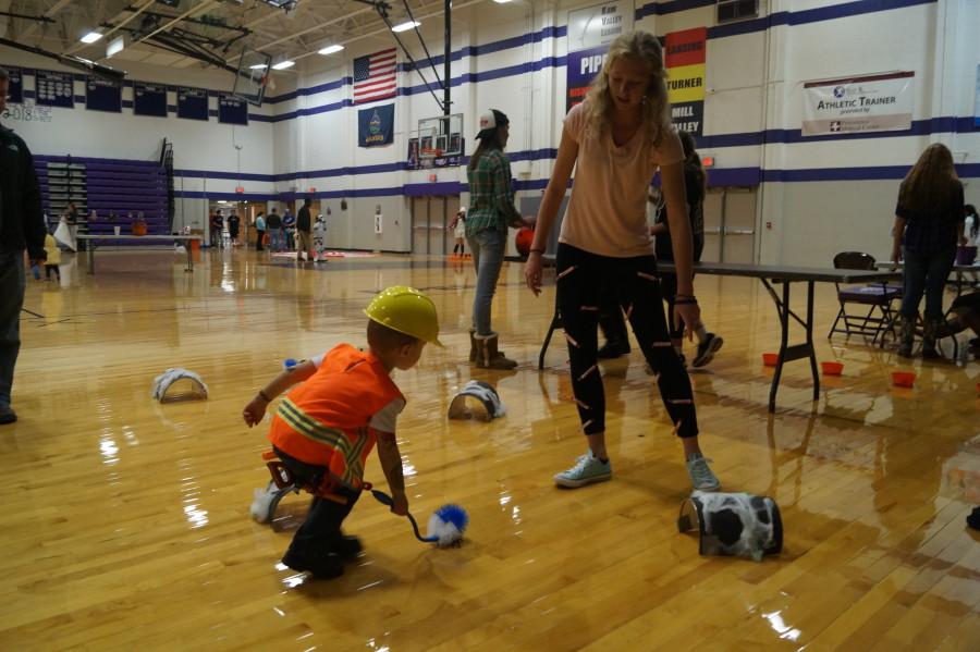 Sophomore Emma Golden gives directions to a little boy trying to get his bug through the tunnels by using a toilet bowl brush. It took many tries, but the little boy finally succeeded and received his piece of candy. 