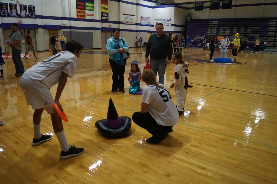 Freshmen Colton Lloyd and Alison Henry work together to run the ring toss station. After every ring made around the witch hat Colton and Alison remembered to congratulate each kid with a piece of candy.