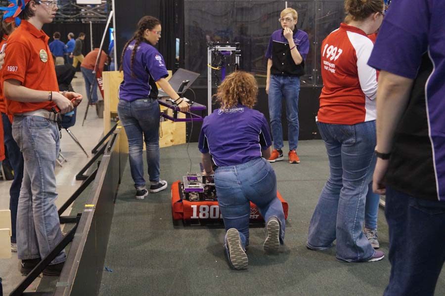 Working on the bot before their next round the team tries mounting on the sides of the other robot but is unsuccessful.