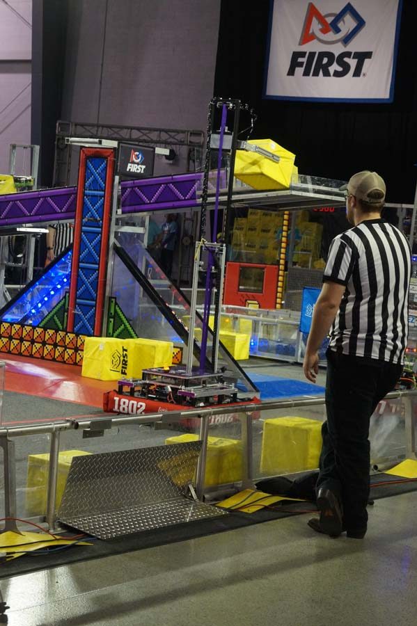 As the Piper robot puts a block on scoring points for their team the judge watches to make sure no fouls are being committed.
